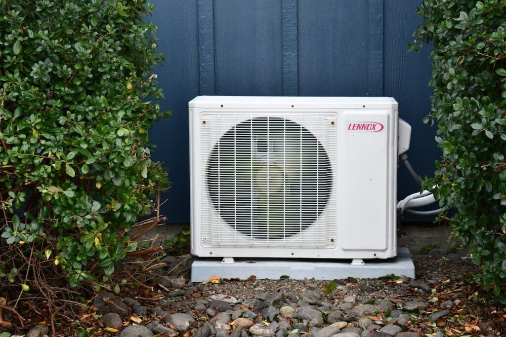 Lennox mini split air conditioner unit in between bushes.