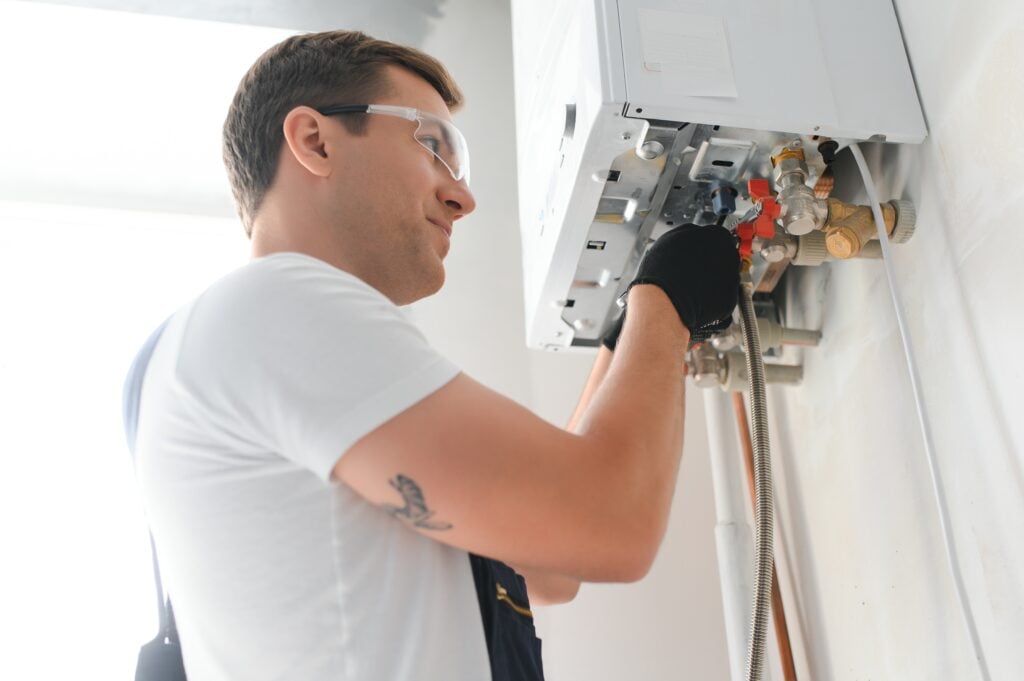 Professional boiler service: qualified technician checking a natural gas boiler at home. tankless water heater cost