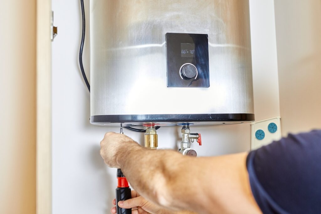 what size water heater do I need Man tightens the pipe nut in the water heating system. The master installs the water heater. The concept of bathroom maintenance.