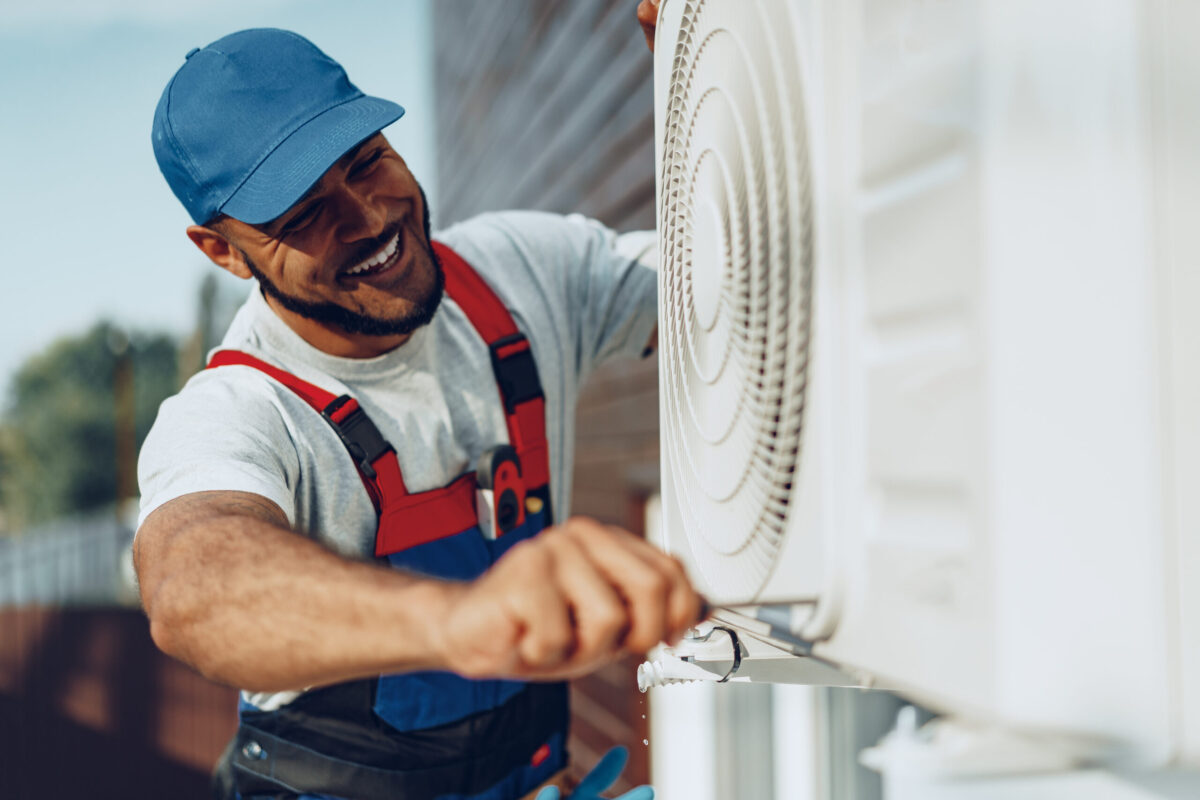 Young black man repairman checking an outside air conditioner unit close up
