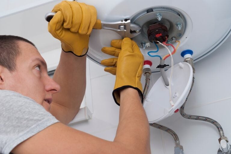 repairman with a wrench in his hand tightens the nuts on an electric boiler