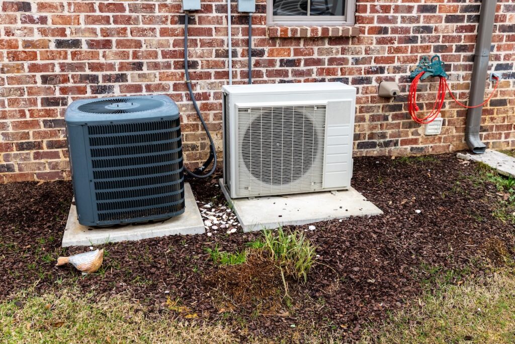 types of hvac systems HVAC Air Conditioner Compressor and a Mini-split system together next to each other, next to a brick home.