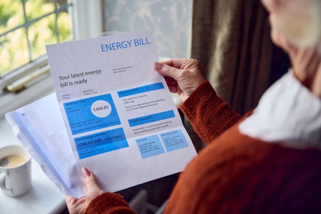 Two air source heat pump units installed on a modern house Close Up Of Senior Woman Opening UK Energy Bill Concerned About Cost Of Living Energy Crisis