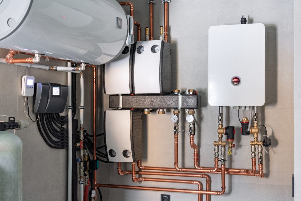 energy efficient water heater Heating system equipment in a boiler room of modern private house. Wall installation of electric boiler device, valves, pumps, cooper tubing, water heater, automatic controller in a single family home