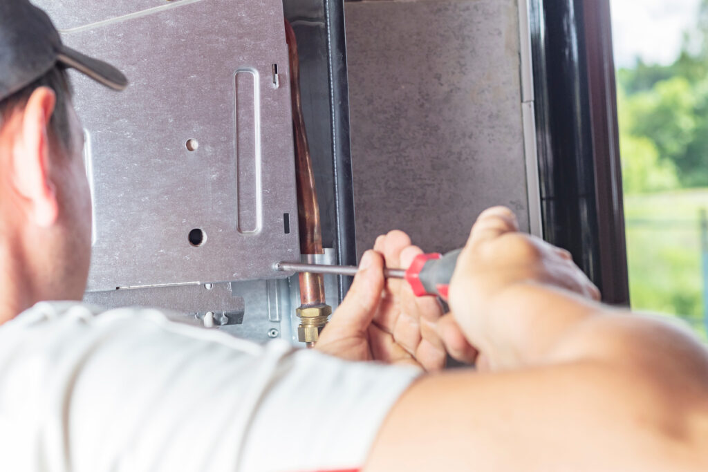 emergency furnace repair The master sets up a gas boiler, which weighs on the wall. The front dashboard is open. The removal and installation of gas nozzles for gas supply.
