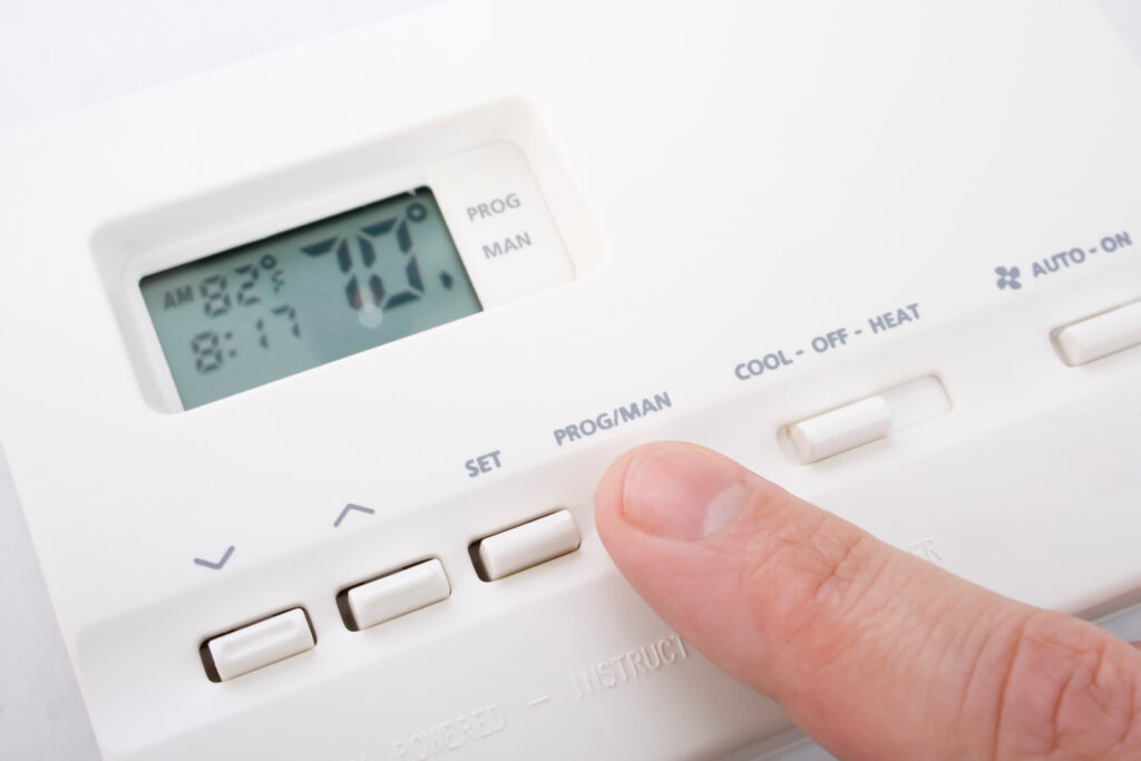 recommended thermostat settings for summer and winter Closeup shot of male hand adjusting thermostat to 70 degrees
