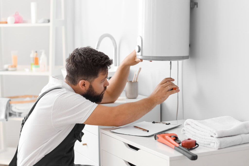 how does a hot water heater work Male plumber repairing boiler with screwdriver in bathroom