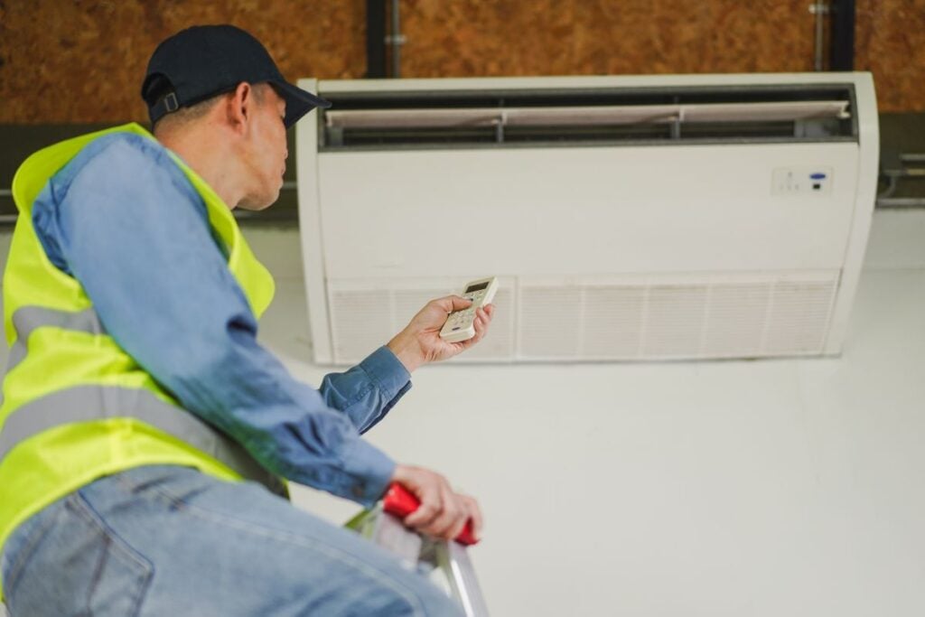 cooling installation worker testing air flow in air conditioner inside house