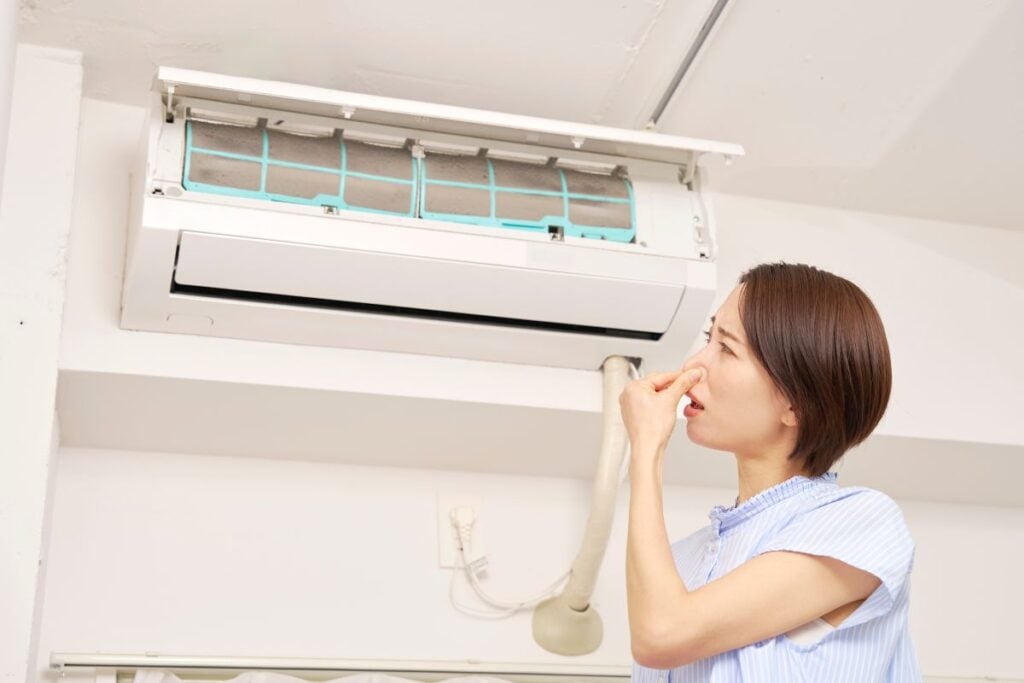 hvac repair cost asian woman covering nose bad smell from air conditioner inside family house