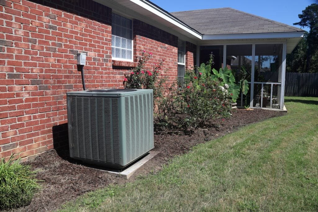 Air Conditioner system next to a home, modern clean with bushes and brick wall