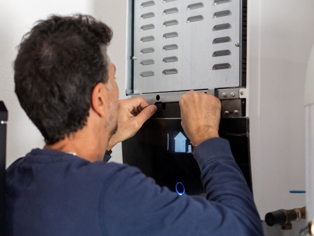 worker using blue shirt installing hybrid water heater modern unit
