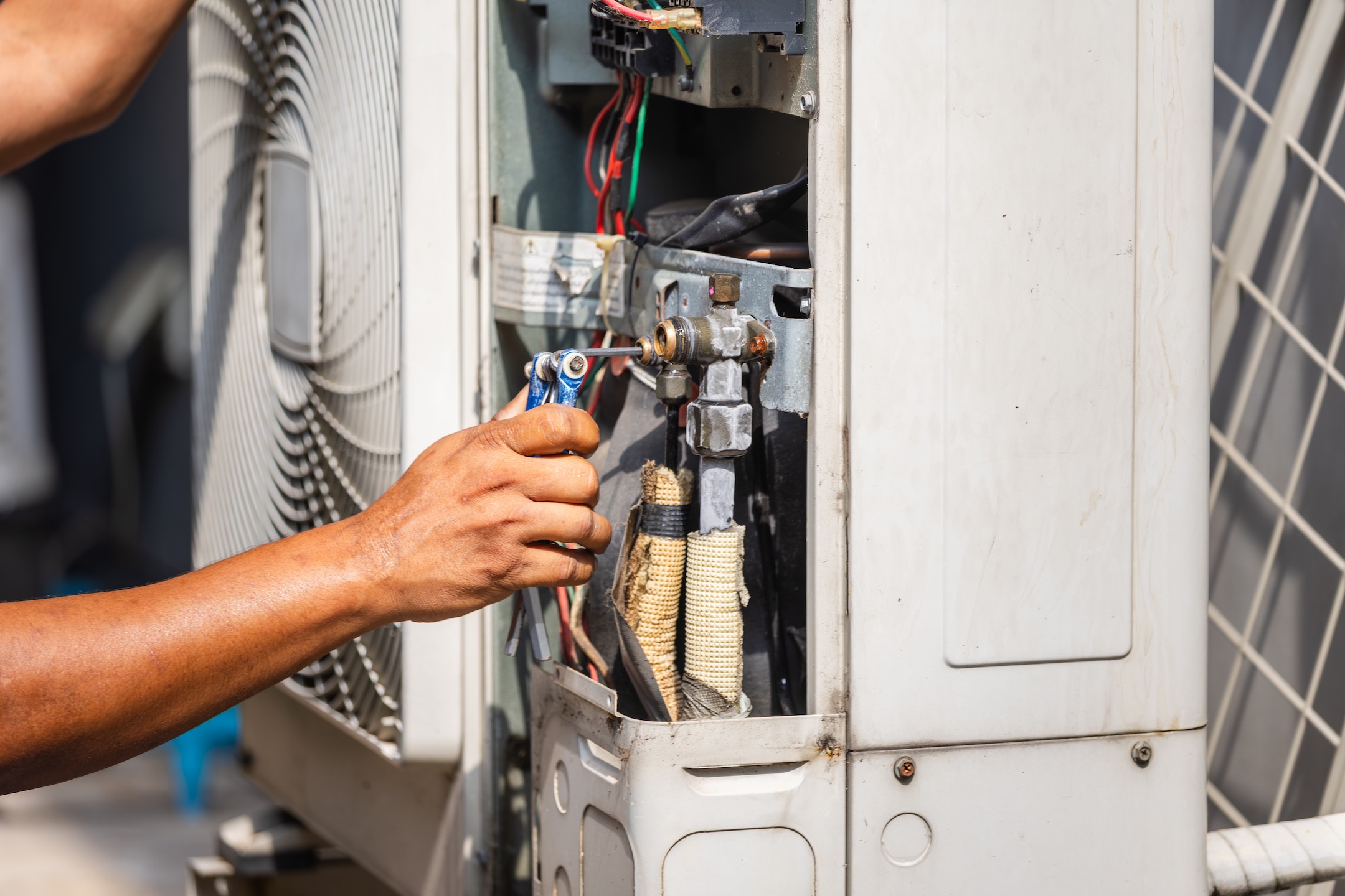 Technician performing maintenance service on home air conditioning system,