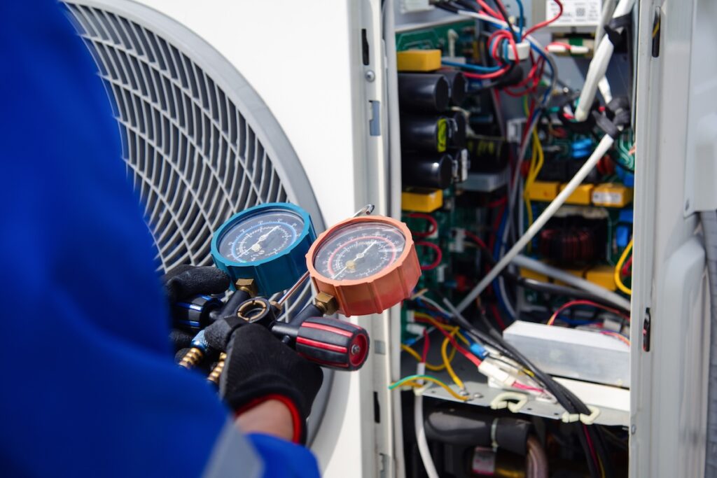 air conditioner technician is using a gauge to measure the refrigerant pressure. air compressor.
