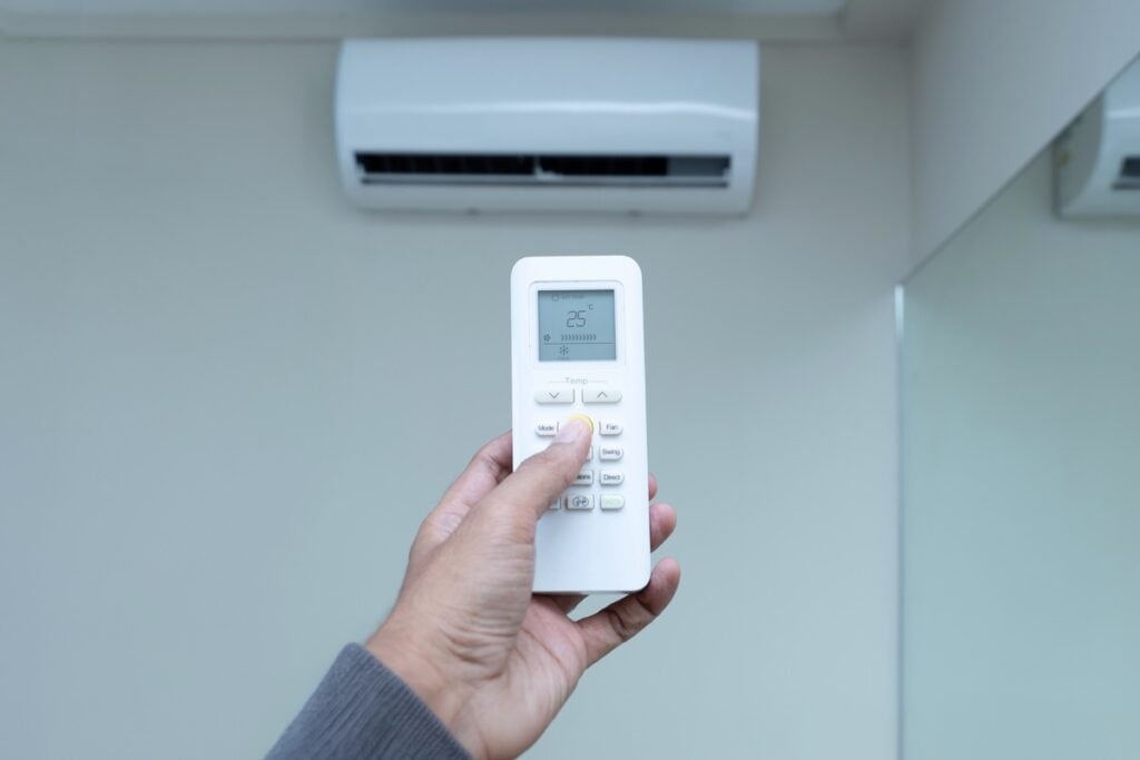 A hand holds an air conditioner remote control,