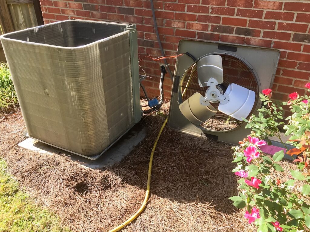 Maintenance being performed on a HVAC Air Conditioner system, with the fan off of the condenser unit.