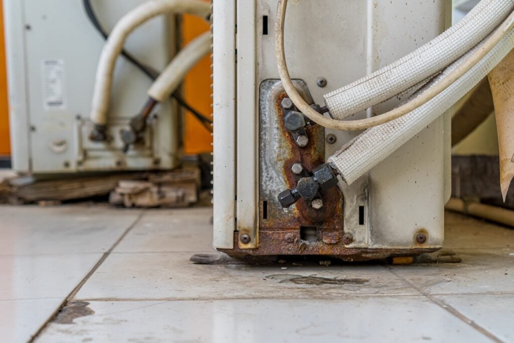 Two air conditioning units exhibit signs of leakage and rust, indicating potential maintenance issues or the need for replacement Perfect for HVAC or home repair themes.