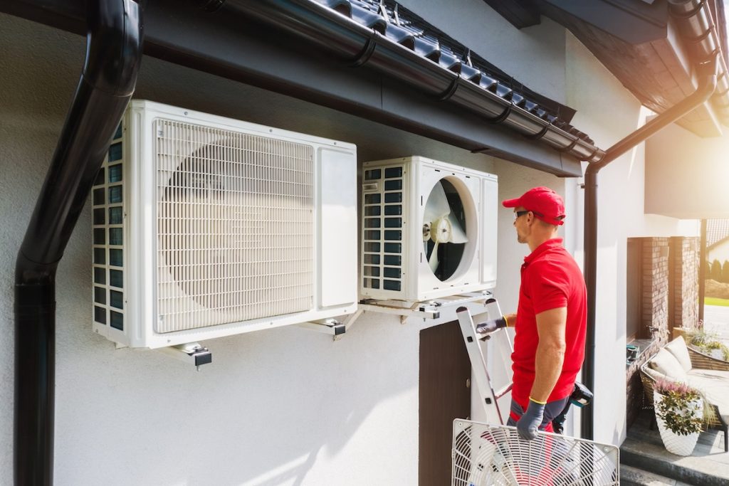 Professional HVAC Technician Performing Air Condition and Heat Pump Units Maintenance. Residential Heating and Cooling Theme.